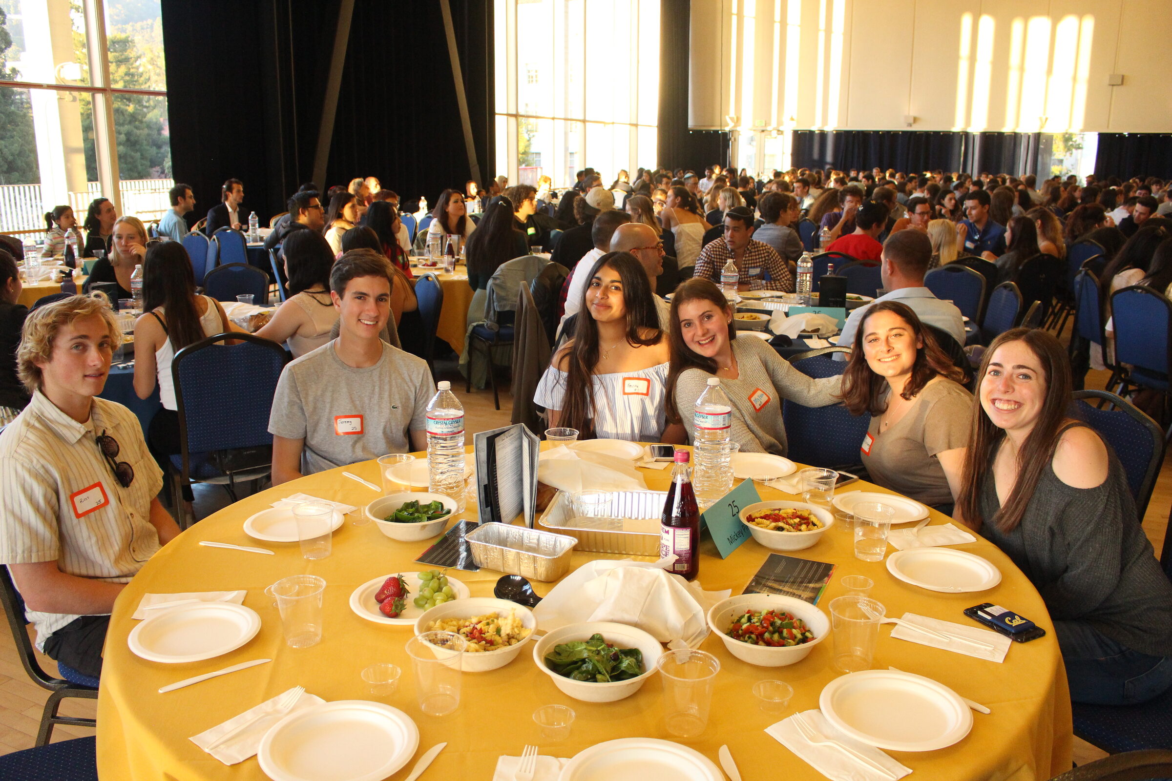 A packed hall of students at long tables for a Shabbat dinner of five hundred