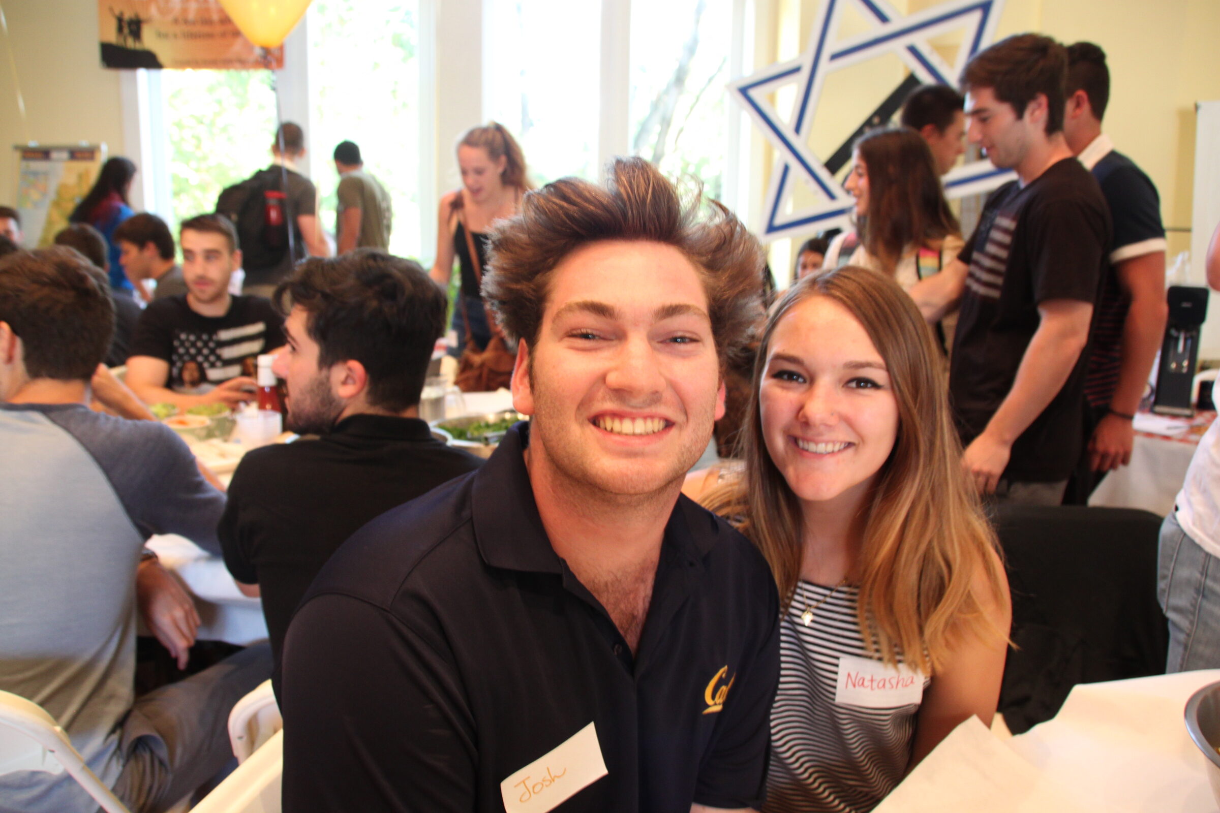 Two students smiling at a crowded indoor Welcome Week gathering
